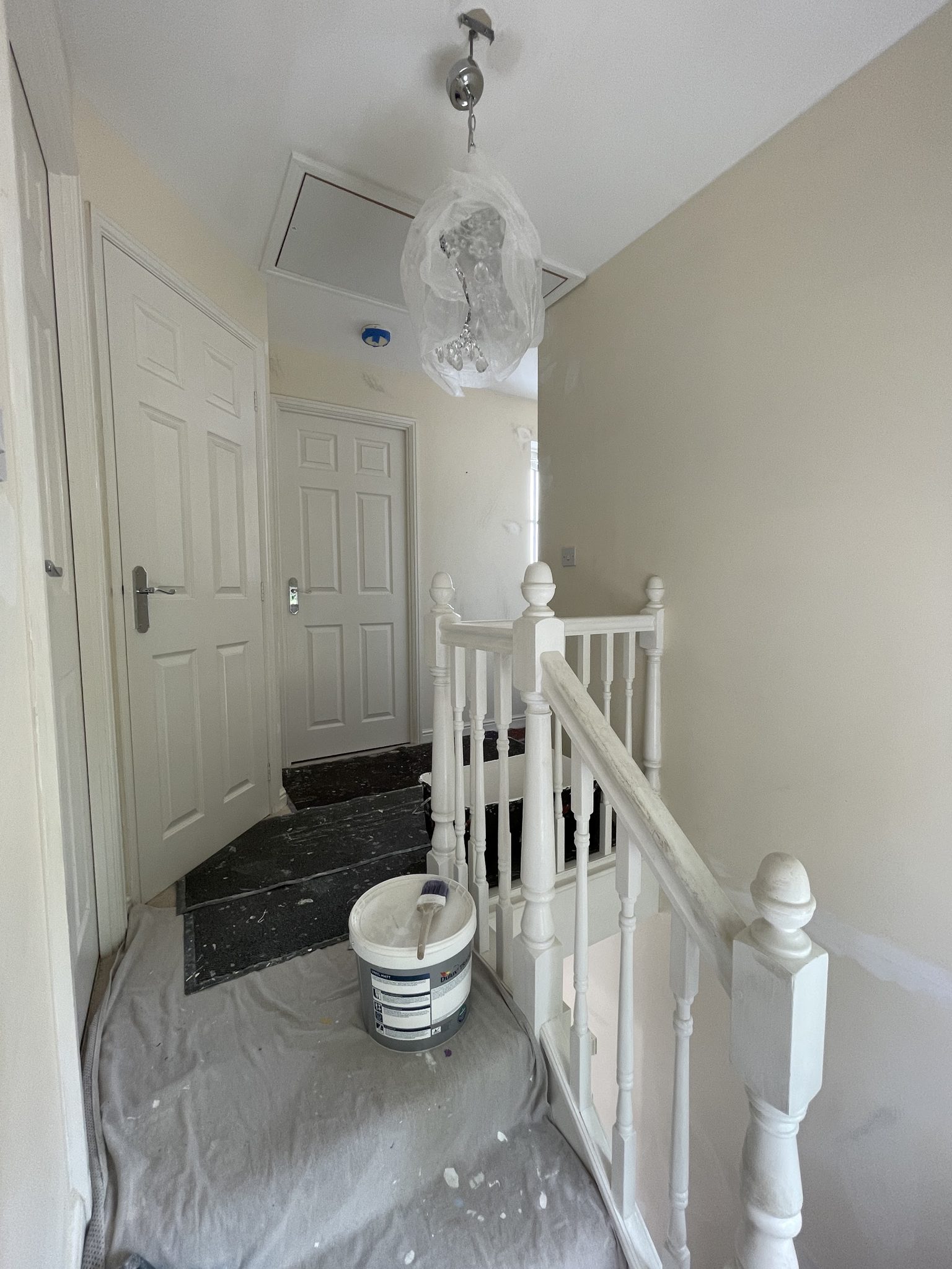 Hallway and landing mid-job, dust sheets down and woodwork in white