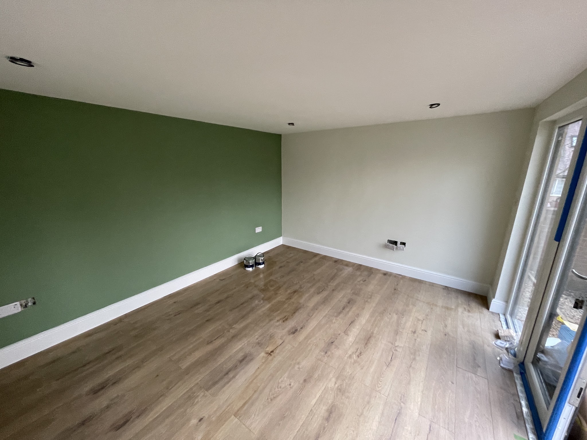 Living room with a deep green feature wall, white ceiling and crisp white skirting