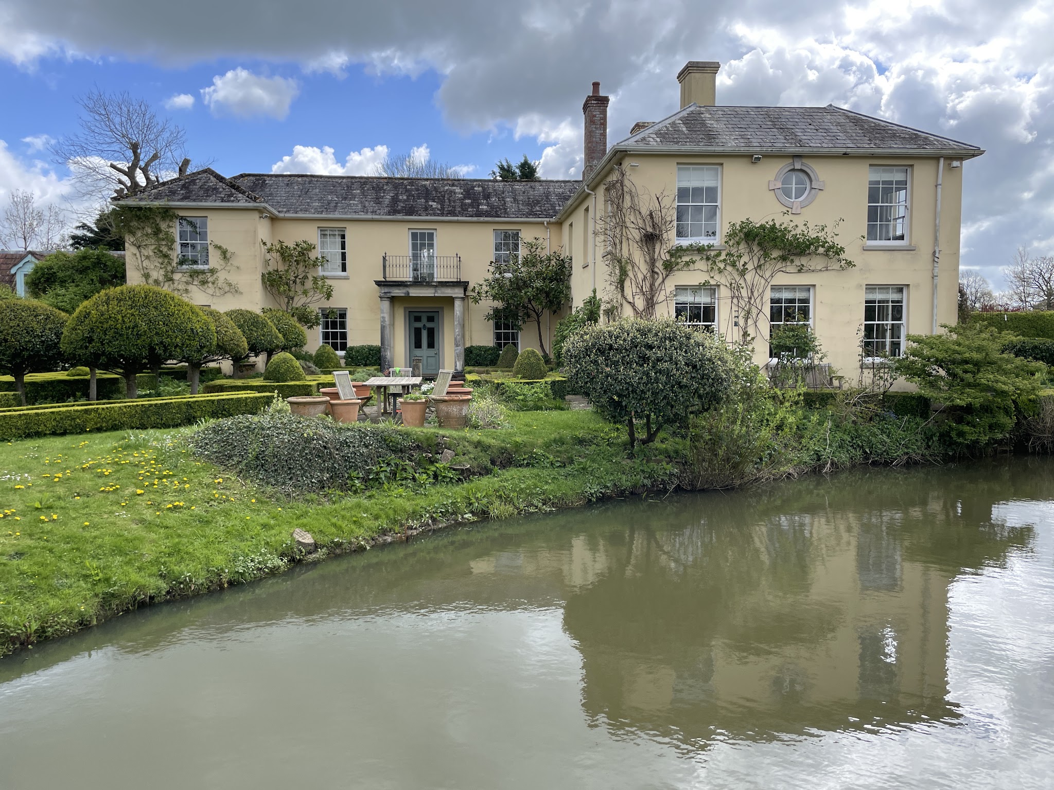 Cream period country house beside a pond