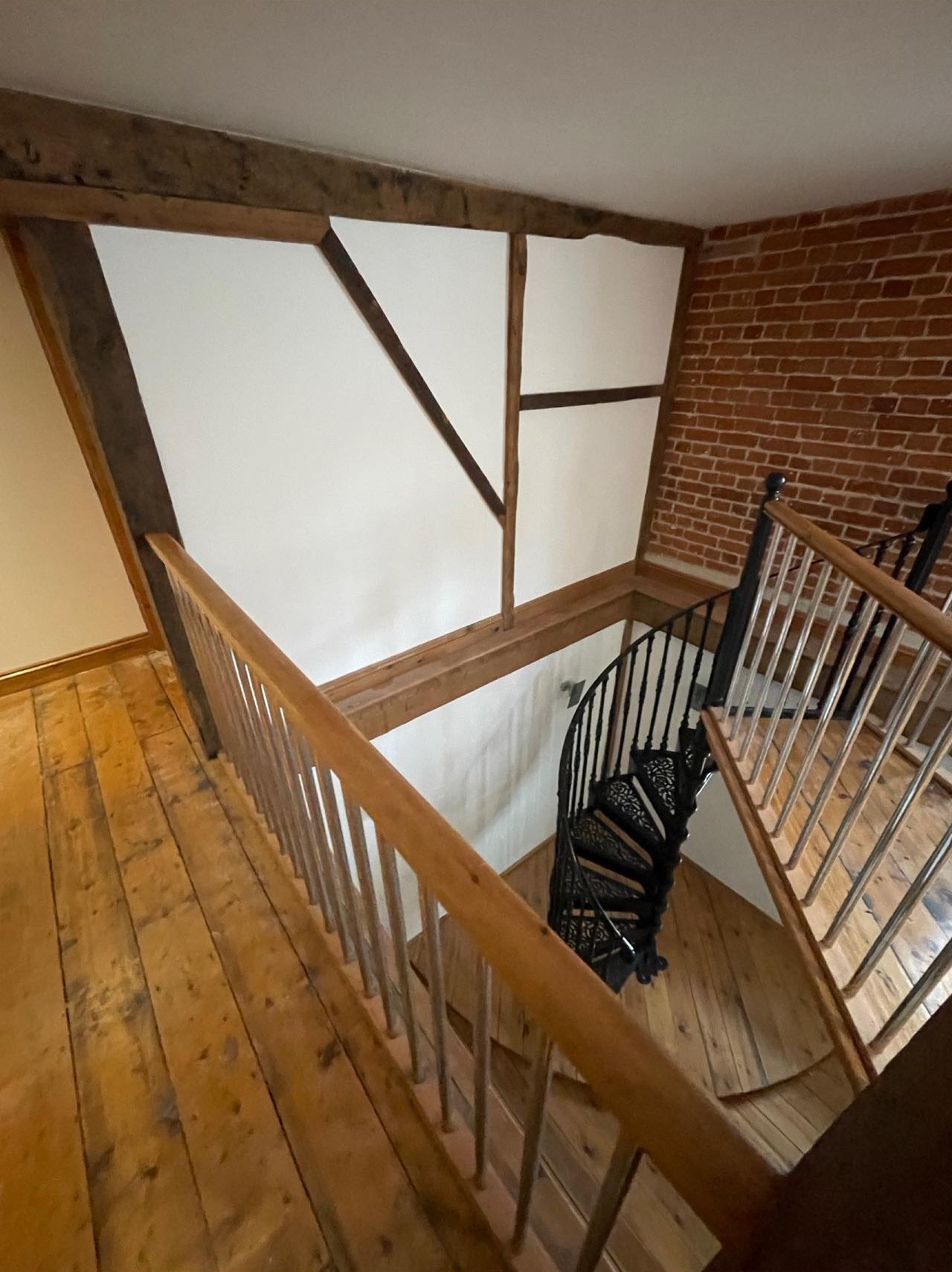 Timber framed landing with white painted panels and a brick wall